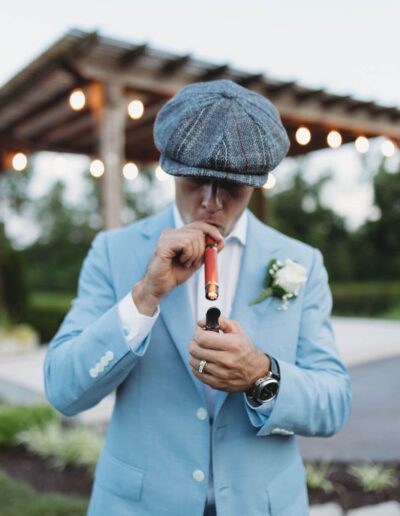 Groom wearing his custom light blue suit from Tailored Gents at Savile Row smoking a cigar.