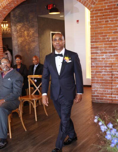 Groom wearing a custom wedding tuxedo from Tailored Gents at Savile Row walking down the aisle.