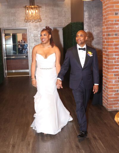 Groom wearing a custom wedding tuxedo from Tailored Gents at Savile Row walking with his bride.