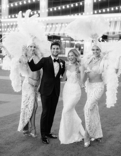 Groom wearing a custom wedding tuxedo from Tailored Gents at Savile Row posing with his bride and showgirls.