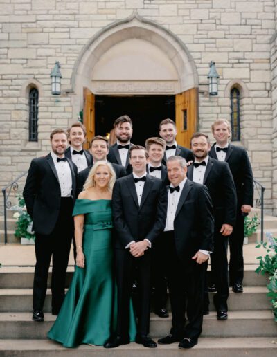 Groom wearing a custom wedding tuxedo from Tailored Gents at Savile Row posing with his parents and groomsmen.