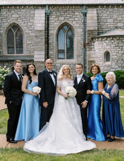 Groom wearing a custom tuxedo from Tailored Gents at Savile Row posing with the bride and family.